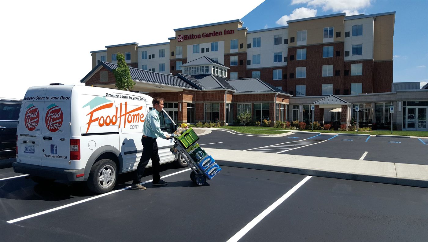 A FoodHome.com driver delivering groceries from the branded van